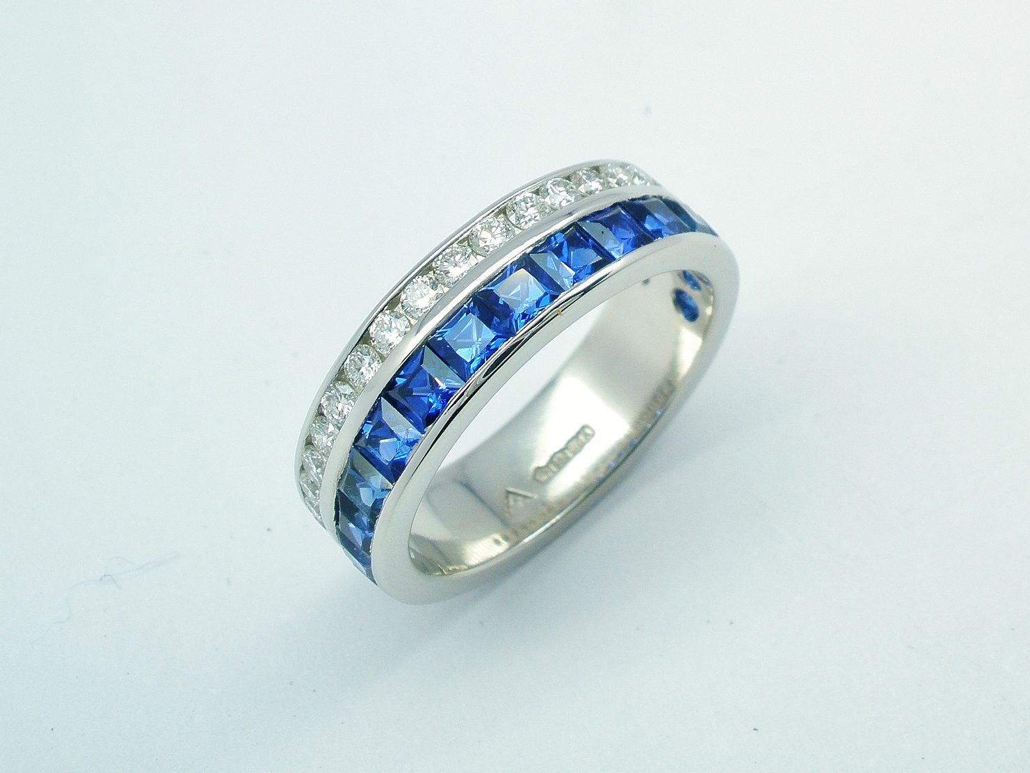 A 37 stone square cut sapphire and round brilliant cut diamond ring channel set in a 5mm broad flat heavy sectioned platinum band.