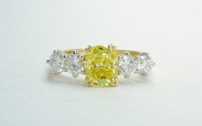A 5 stone HTHP treated canary yellow cushion shaped diamond and round brilliant cut diamond ring mounted in 18ct yellow gold and platinum.