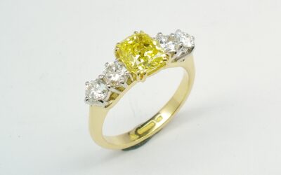 A 5 stone HTHP treated canary yellow cushion shaped diamond and round brilliant cut diamond ring mounted in 18ct yellow gold and platinum.