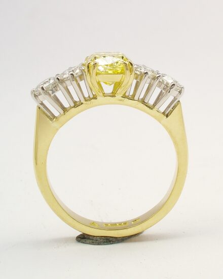 A 5 stone HTHP treated canary yellow cushion shaped diamond and round brilliant cut diamond ring mounted in 18ct yellow gold and platinum.
