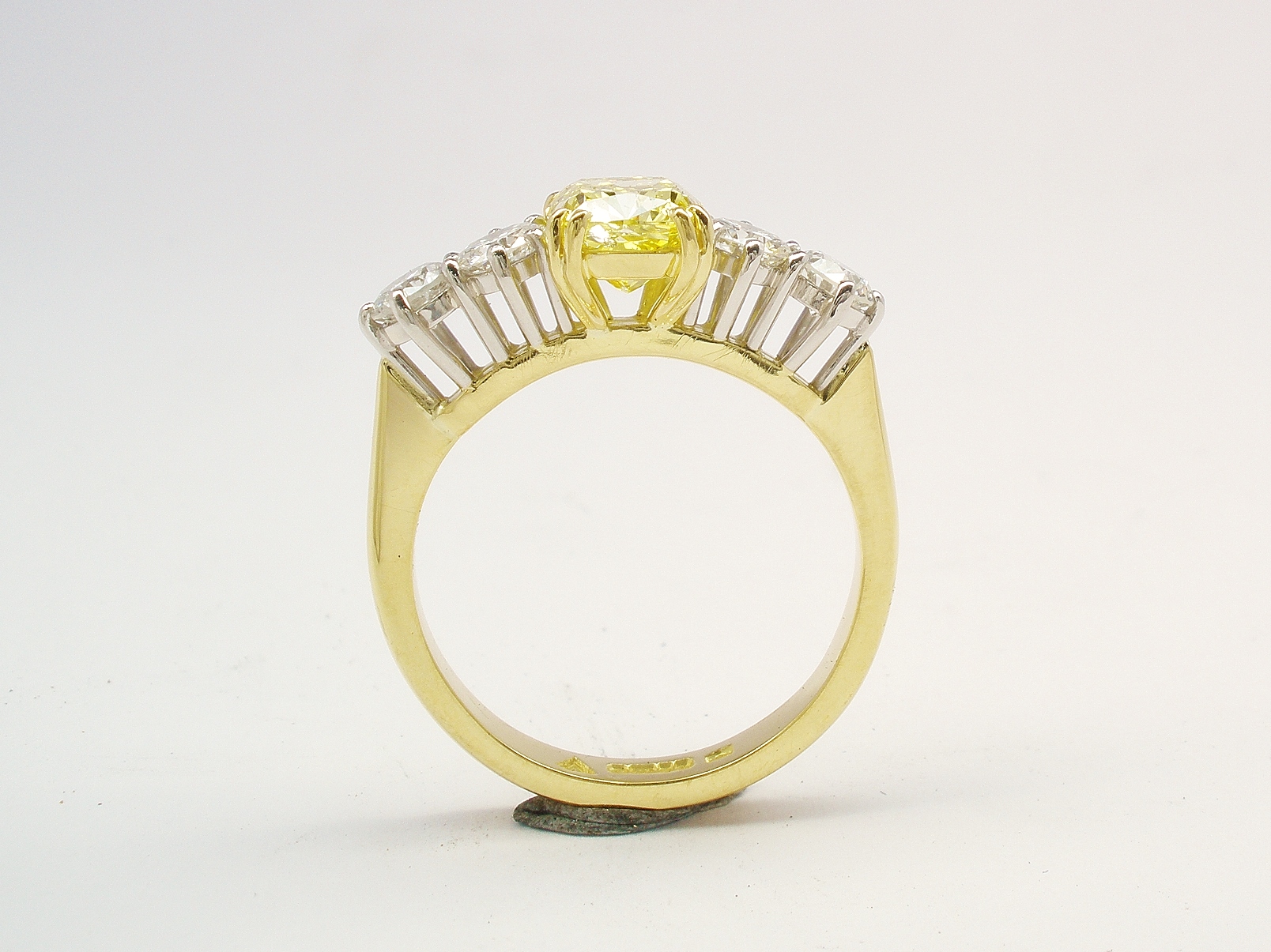 A 5 stone HTHP treated canary yellow cushion shaped diamond and round brilliant cut diamond ring mounted in 18ct yellow gold and platinum.