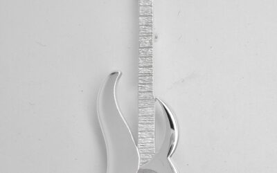 A sterling silver kilt pin taking the form loosely of an electric guitar. The main body is of stylised initials 'S & M'.