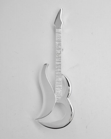 A sterling silver kilt pin taking the form loosely of an electric guitar. The main body is of stylised initials 'S & M'.