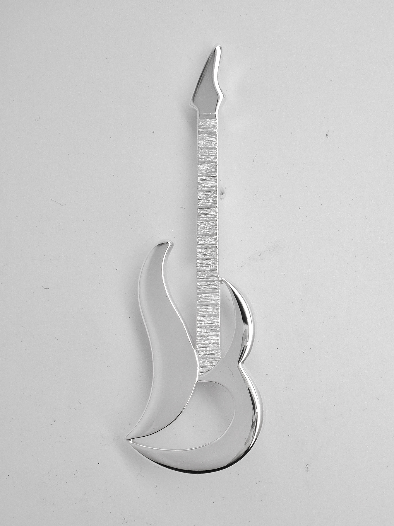 A sterling silver kilt pin taking the form loosely of an electric guitar. The main body is of stylised initials 'S & M'.