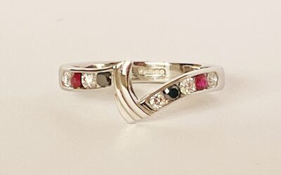 A 9 stone round brilliant cut white diamond, black diamond & ruby ring mounted in platinum and shaped to fit between a 3 stone marquise ruby & diamond ring and 3 stone diamond shaped wedding ring.