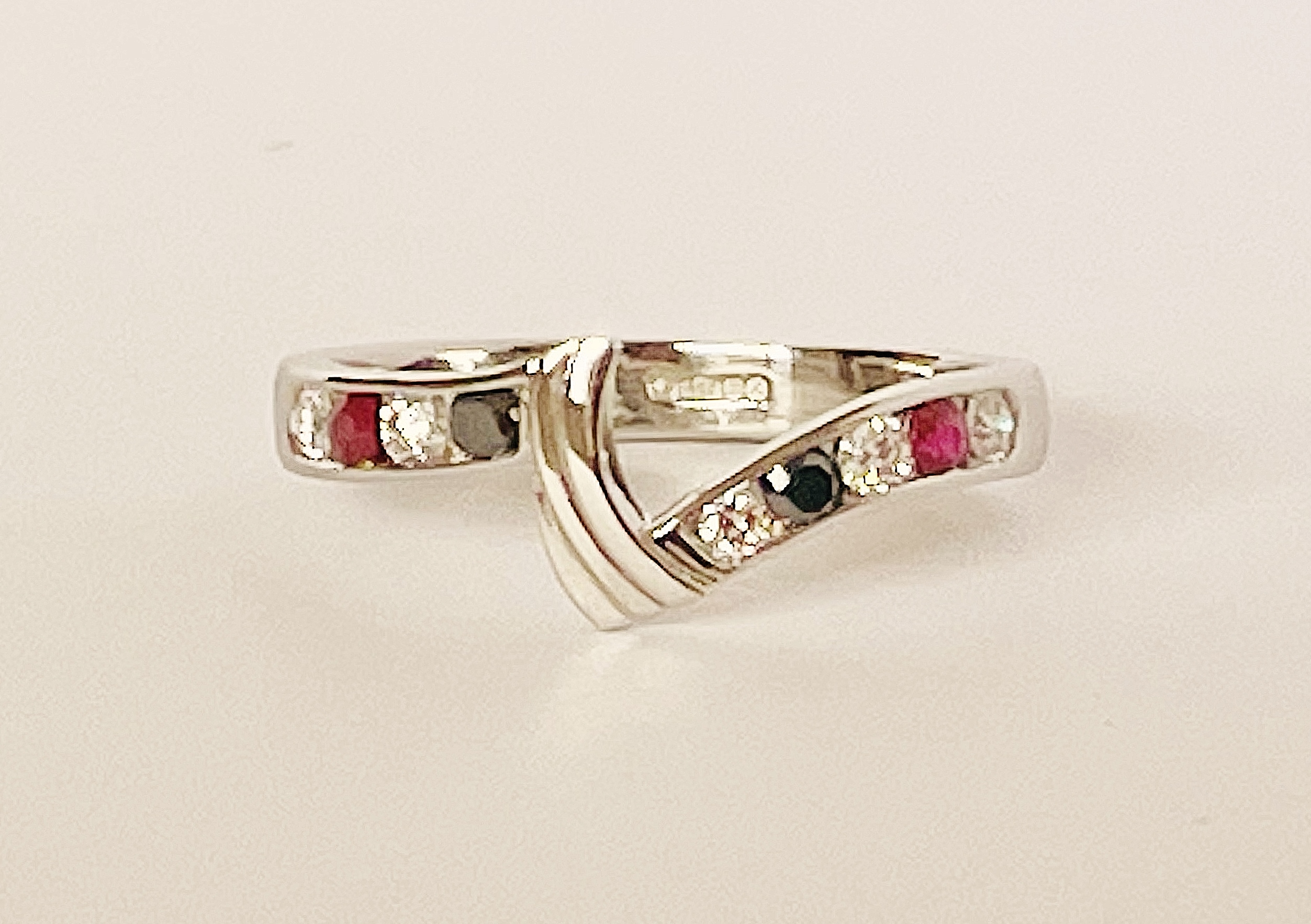 A 9 stone round brilliant cut white diamond, black diamond & ruby ring mounted in platinum and shaped to fit between a 3 stone marquise ruby & diamond ring and 3 stone diamond shaped wedding ring.