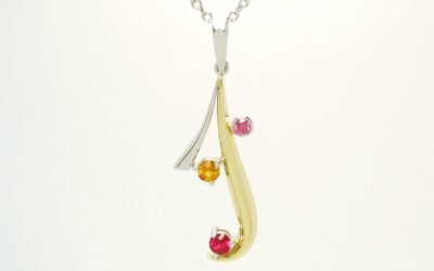 An 18ct yellow gold and platinum pendant loosely designed on an initial 'J' set with a ruby, topaz and purple diamond.