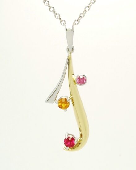 An 18ct yellow gold and platinum pendant loosely designed on an initial 'J' set with a ruby, topaz and purple diamond.