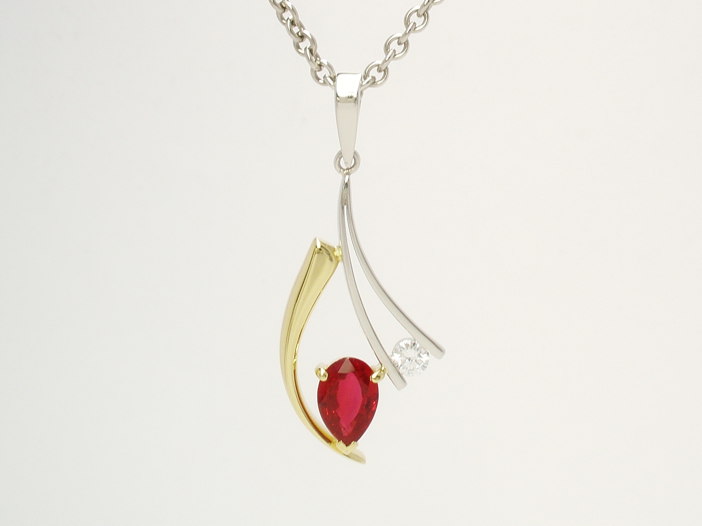 A 2 stone pear ruby and round brilliant cut diamond pendant mounted in 18ct. yellow gold and platinum.