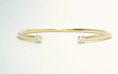A 9ct. yellow gold childs' torque bangle rub-over set with 2 small lab grown round brilliant cut diamonds.