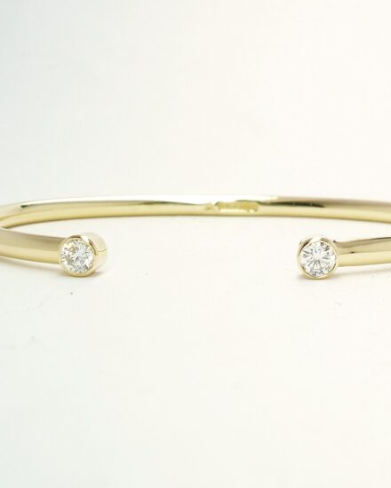 A 9ct. yellow gold childs' torque bangle rub-over set with 2 small lab grown round brilliant cut diamonds.