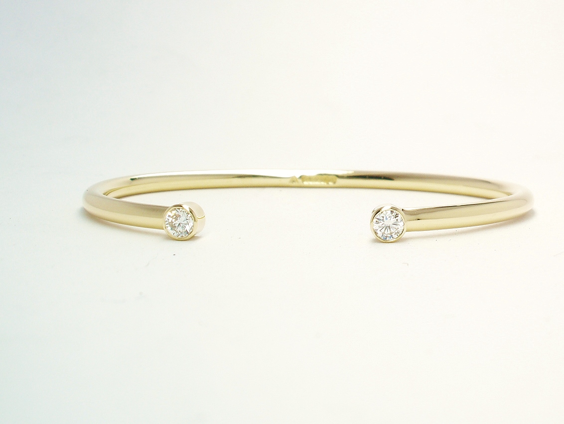 A 9ct. yellow gold childs' torque bangle rub-over set with 2 small lab grown round brilliant cut diamonds.