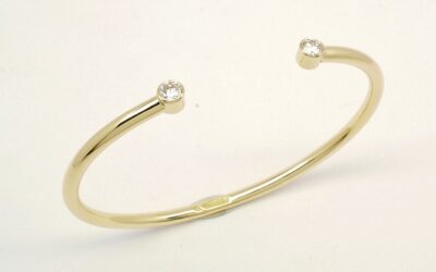 A 9ct. yellow gold childs' torque bangle rub-over set with 2 small lab grown round brilliant cut diamonds.