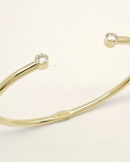 A 9ct. yellow gold childs' torque bangle rub-over set with 2 small lab grown round brilliant cut diamonds.