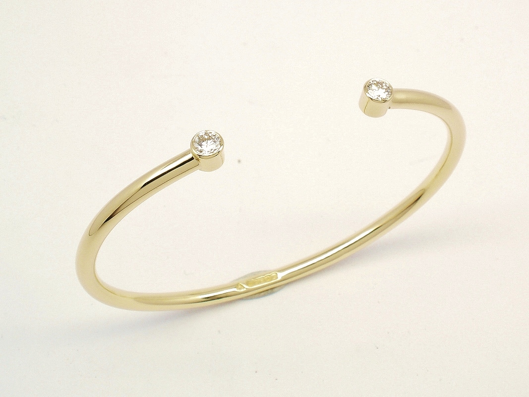 A 9ct. yellow gold childs' torque bangle rub-over set with 2 small lab grown round brilliant cut diamonds.
