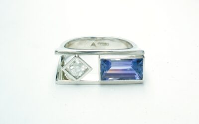 A 2 stone baguette cut Tanzanite and round brilliant cut diamond ring, mounted in platinum with a plateau top.