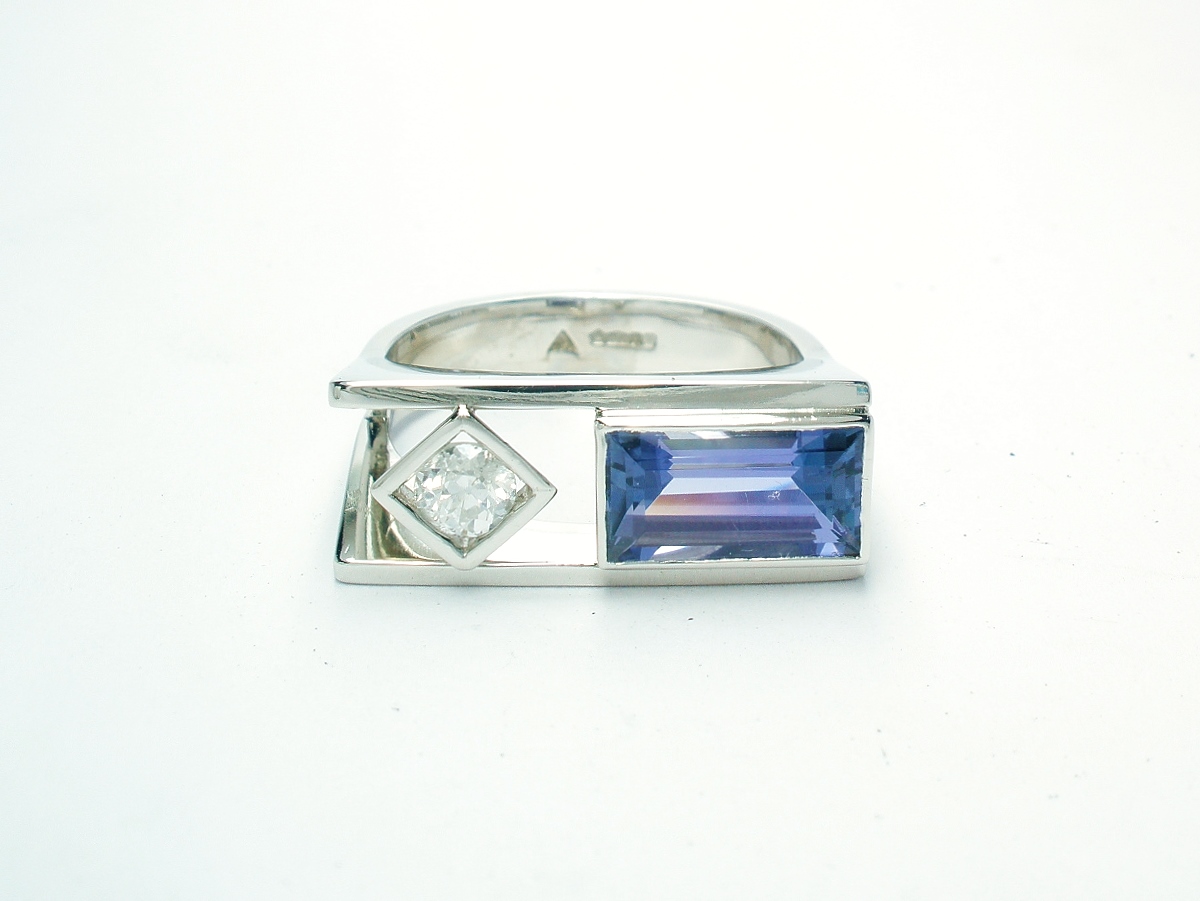 A 2 stone baguette cut Tanzanite and round brilliant cut diamond ring, mounted in platinum with a plateau top.