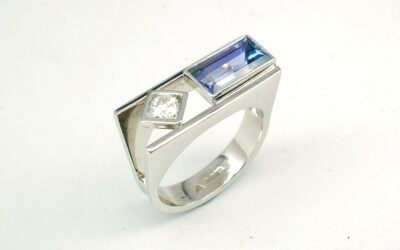 A 2 stone baguette cut Tanzanite and round brilliant cut diamond ring, mounted in platinum with a plateau top.