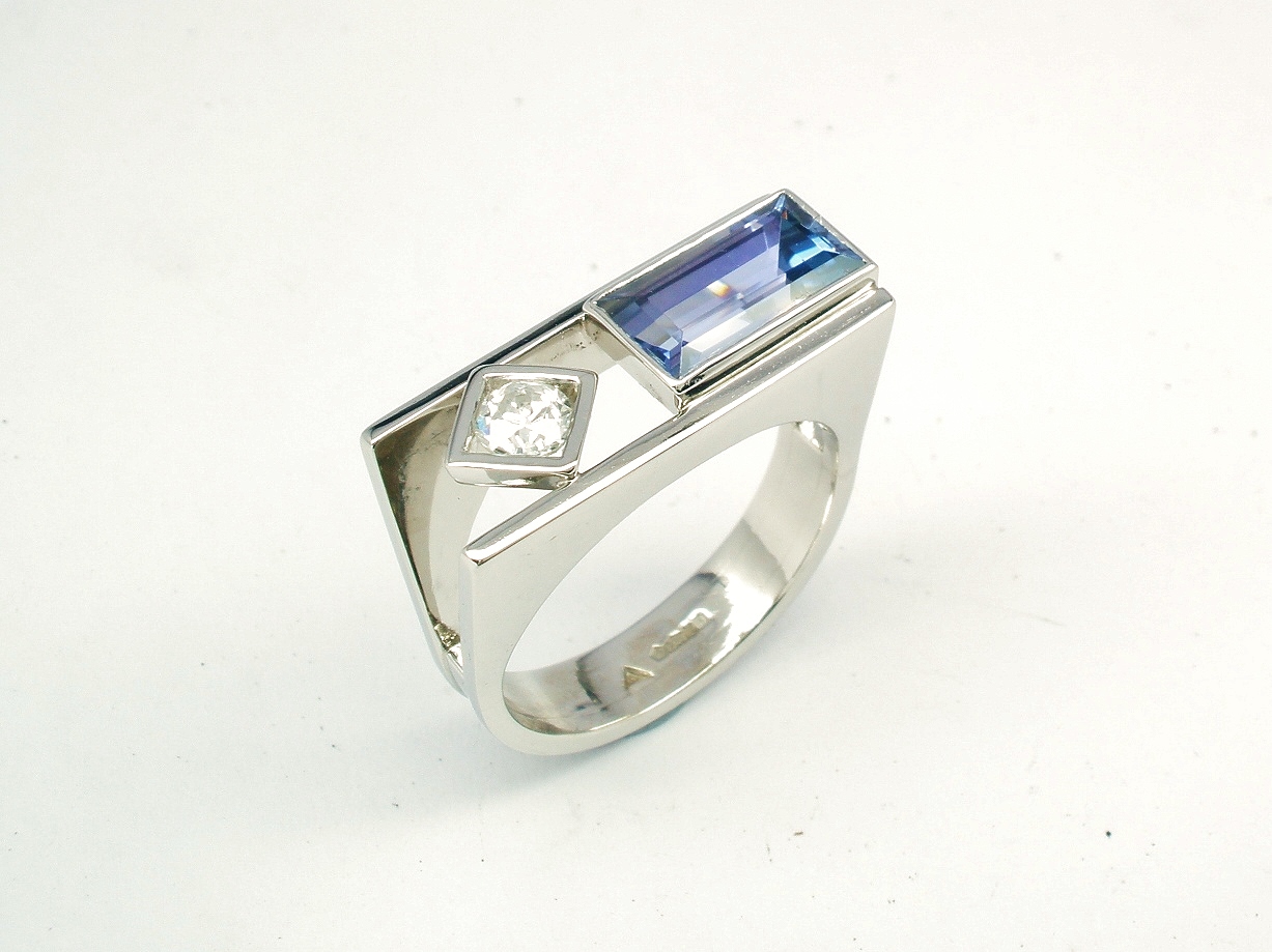 A 2 stone baguette cut Tanzanite and round brilliant cut diamond ring, mounted in platinum with a plateau top.