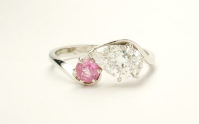 A 2 stone pear shaped Lab grown diamond and round pink sapphire cross-over style ring mounted in platinum.