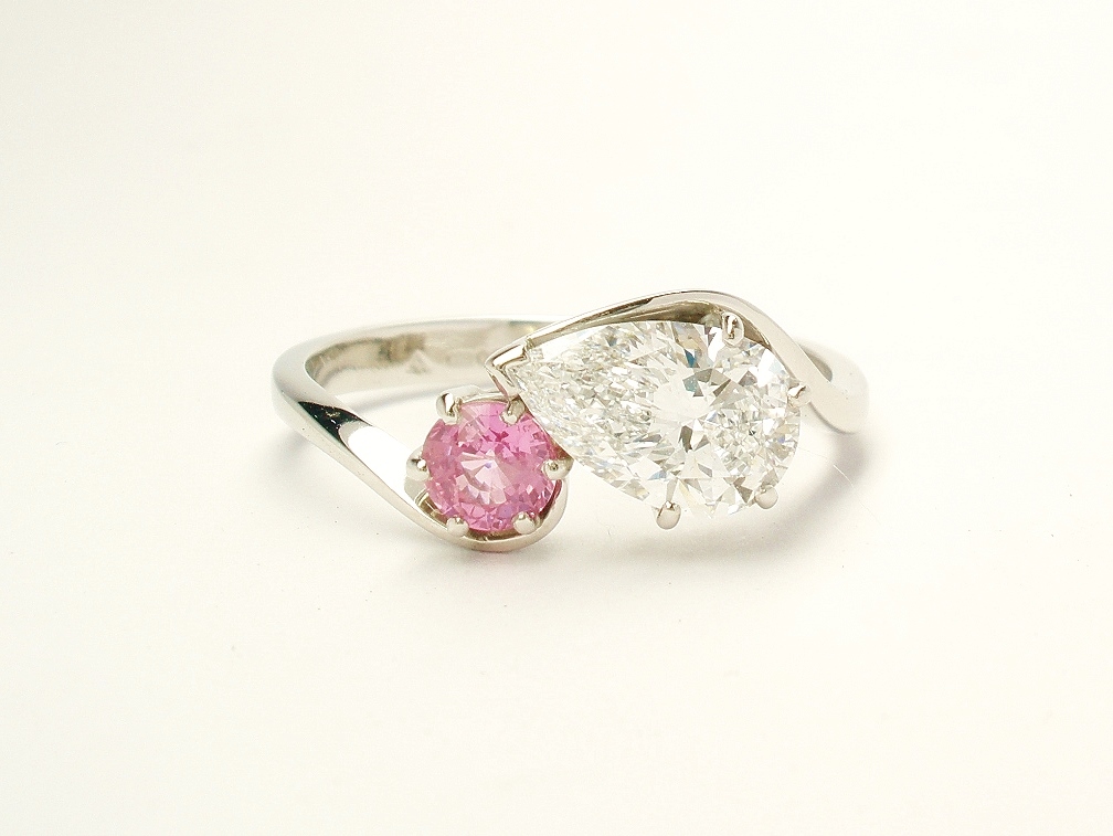 A 2 stone pear shaped Lab grown diamond and round pink sapphire cross-over style ring mounted in platinum.