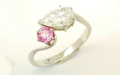 A 2 stone pear shaped Lab grown diamond and round pink sapphire cross-over style ring mounted in platinum.