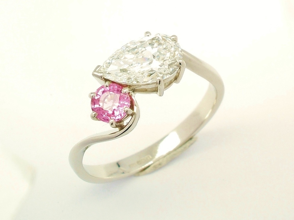 A 2 stone pear shaped Lab grown diamond and round pink sapphire cross-over style ring mounted in platinum.