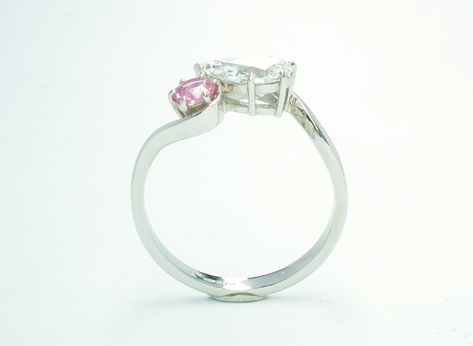 A 2 stone pear shaped Lab grown diamond and round pink sapphire cross-over style ring mounted in platinum.