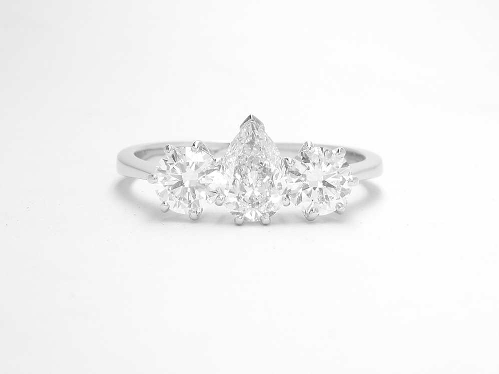 A 3 stone pear diamond and round brilliant cut diamond ring mounted in platinum.