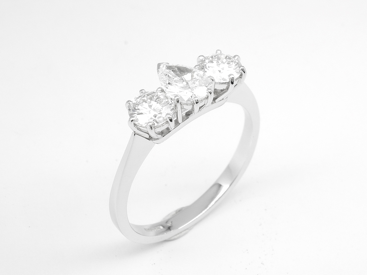 A 3 stone pear diamond and round brilliant cut diamond ring mounted in platinum.
