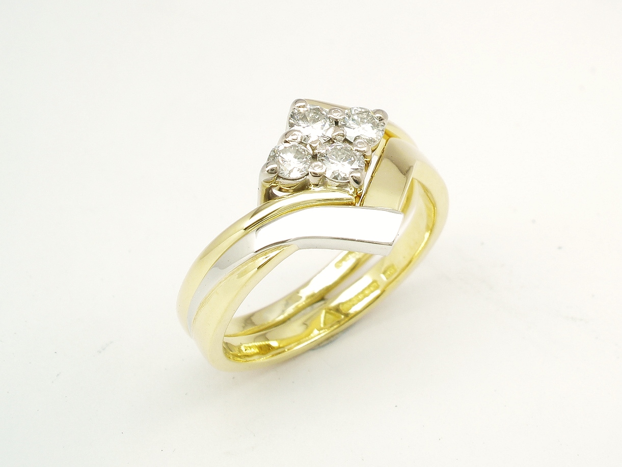 An 18ct. yellow gold and platinum shaped to fit around a 4 stone round brilliant cut diamond cross-over ring.
